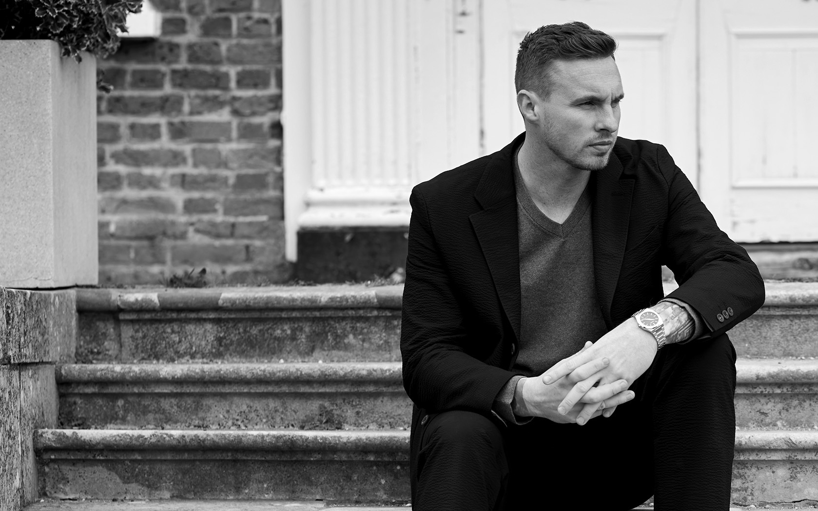 David Stockdale sitting on some steps outside wearing a blazer