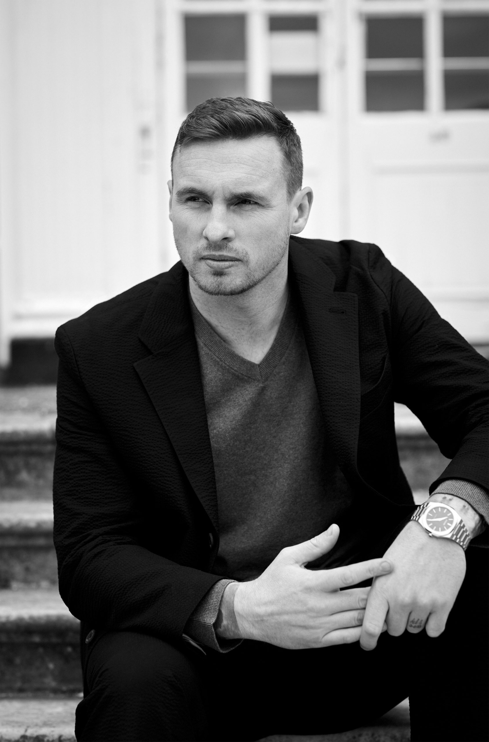 David Stockdale sitting on some steps outside wearing a blazer