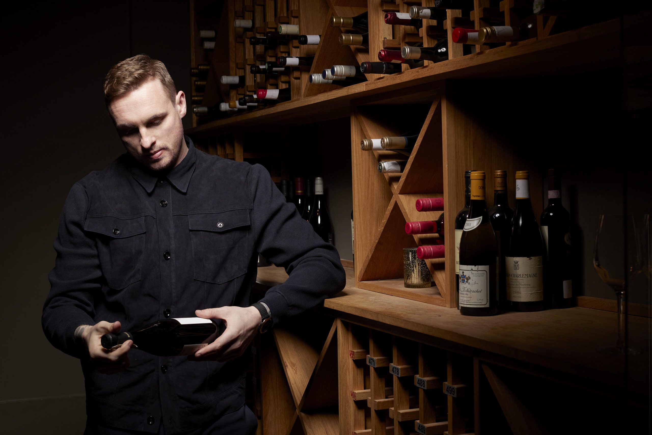 David Stockdale holding a bottle of wine in a wine cellar